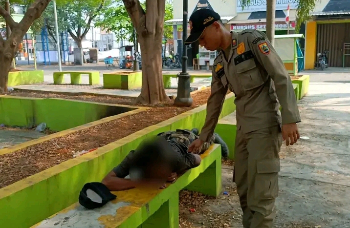 Petugas Satpol PP Pemalang sedang membangunkan anak jalanan yang sedang tidur di Taman Mochtar pemalang