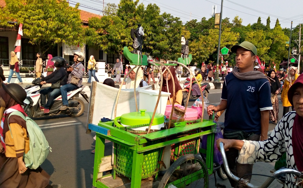 Manto Penjual Es Dawet mendorong gerobak daganganya pulang.