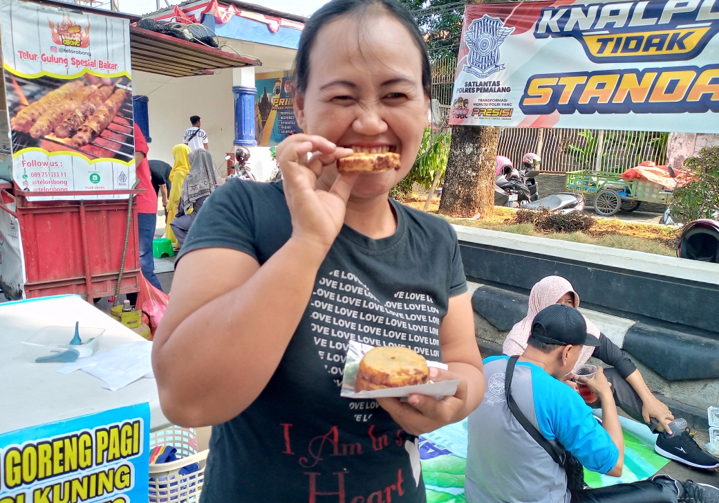 Seorang pembeli pisang Lumpur sedang menikmati'lezat nya jajanan khas pemalang