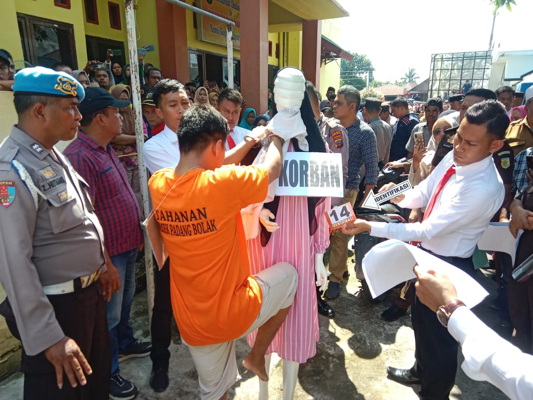 Tersangka memeragakan adegan menendang perut korban memakai dengkul saat pra rekonstruksi dugaan tindak pidana pembunuhan berencana terhadap korban yang jasadnya ditemukan di Selokan pembuangan air Kantor Dinsos Paluta beberapa waktu lalu