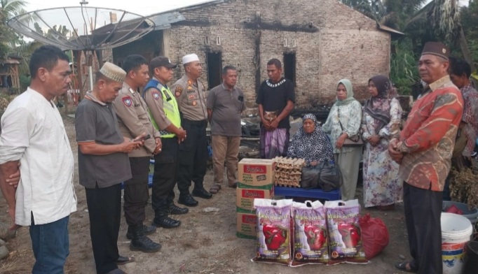 Di depan puing Rumah yang terbakar, Kapolsek Padang Bolak, AKP Harun Manurung, dan anggota datang menyantuni para korban dan keluarga, usai kebakaran hebat melanda kawasan tersebut