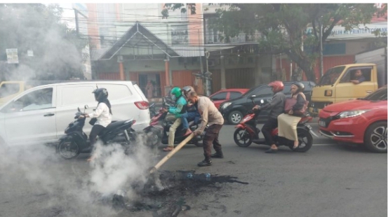 Polisi saat membersihkan ban yang dibakar usai aksi.