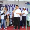 Bupati Jombang Warsubi (tengah) tersenyum saat mendampingi pemenang hadiah umroh dalam momen pengundian doorprize May Day di Stadion Jombang,