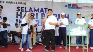 Bupati Jombang Warsubi (tengah) tersenyum saat mendampingi pemenang hadiah umroh dalam momen pengundian doorprize May Day di Stadion Jombang,