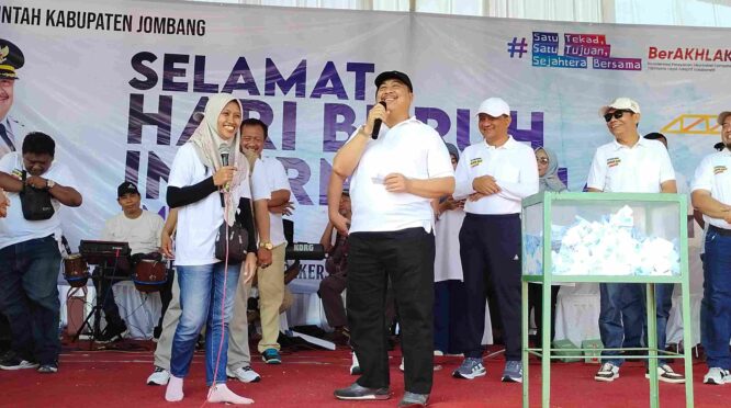 Bupati Jombang Warsubi (tengah) tersenyum saat mendampingi pemenang hadiah umroh dalam momen pengundian doorprize May Day di Stadion Jombang,